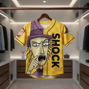 May include: Yellow baseball jersey with a cartoon character design. The jersey features a purple hat, a large face graphic, and the word "SHOCK" in black. The sleeves have additional cartoon faces. The jersey is hanging on a wooden hanger.