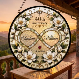 May include: A circular stained glass suncatcher featuring a central infinity symbol, white magnolia flowers, and green leaves. The text reads 40th Anniversary, Charlotte, William, and 10.10.1986, with a small red heart accent in the center.