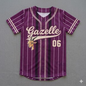May include: Purple baseball jersey with vertical stripes and the word "Gazelle" in a cursive font. The jersey features a cartoon gazelle head and the number "06". The sleeves and collar have white accents.