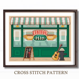 以下が含まれることがあります： テレビ番組「フレンズ」のセントラルパークコーヒーショップのクロスステッチパターン。パターンは、緑色のショップの外装と、「セントラルパーク」と書かれた象徴的なオレンジ色の看板を特徴としています。ショップの前には、茶色のギターと消火栓があります。