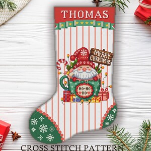 Puede incluir: Un calcetín navideño con un diseño de Papá Noel. El calcetín presenta una parte superior roja con el nombre "THOMAS" y un cuerpo a rayas verdes y blancas. El diseño incluye a Papá Noel en una taza, un bastón de caramelo y las palabras "MERRY CHRISTMAS".