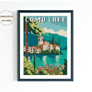 May include: Cross stitch pattern of a vintage travel poster for Como Lake, Italy. The poster features a colorful illustration of a lake with a small town on an island, surrounded by mountains and trees. The text "COMO LAKE" is printed in bold, white letters at the top of the poster.