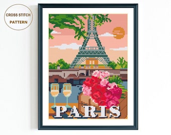 May include: Cross stitch pattern of the Eiffel Tower in Paris, France. The pattern features a pink sky, green trees, a river, two glasses of champagne, and a bouquet of pink and red roses. The word "PARIS" is written in brown letters at the bottom of the pattern.