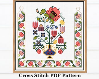 May include: Cross stitch pattern featuring a colorful floral bouquet in a blue and gold vase. The design includes red, pink, yellow, blue, green, and black flowers. The pattern is framed in a wooden frame.