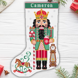 May include: A green and red Christmas stocking featuring a nutcracker design. The stocking is personalised with the name "Cameron" at the top and a rocking horse at the bottom.
