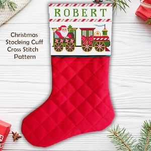 May include: A red Christmas stocking with a quilted pattern. The top cuff features a cross-stitch design of a train with Santa Claus and the name "ROBERT" in green letters. The text "Christmas Stocking Cuff Cross Stitch Pattern" is on the left.