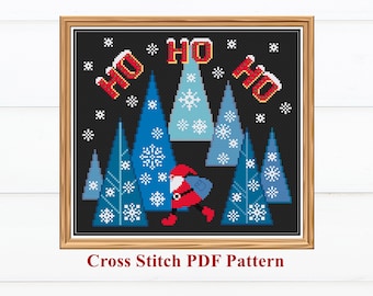 Op de afbeelding: Een ingelijst kruissteekpatroon met een winterlandschap met blauwe bomen, sneeuwvlokken en de kerstman. Het woord "HO" staat in het rood. De tekst "Cross Stitch PDF Pattern" staat onderaan.