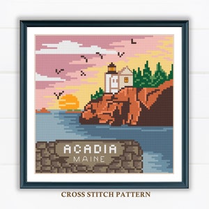 May include: Cross stitch pattern of a lighthouse on a rocky cliff overlooking the ocean at sunset. The sky is pink and orange, and there are birds flying in the air. The text "Acadia Maine" is below the lighthouse.