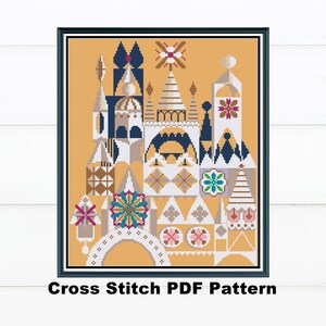 May include: A framed cross-stitch pattern featuring a whimsical architectural design in shades of gold, blue, white, and pink. The pattern includes geometric shapes and floral accents. The text "Cross Stitch PDF Pattern" is at the bottom.