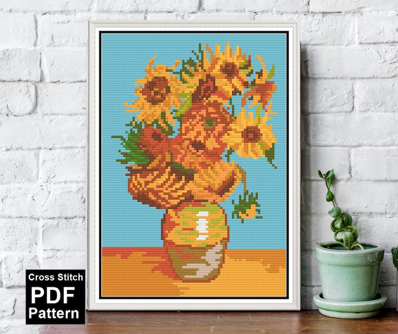 May include: Cross stitch pattern of a vase with sunflowers. The vase is brown and the sunflowers are yellow with green leaves. The background is blue.