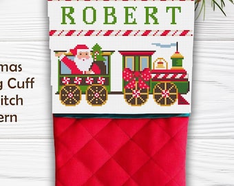 May include: A red quilted Christmas stocking with a white cuff featuring a cross-stitch pattern of a green train carrying Santa Claus. The name ROBERT is stitched in green capital letters above the train, framed by red and white candy cane stripes.