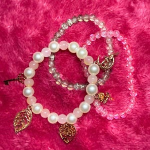 Może przedstawiać: Zestaw trzech ceramicznych kubków z nakrapianym, matowym wykończeniem. Kubki są w odcieniach kremu, jasnoszarym i ciemnoszarym. Każdy kubek ma prosty, minimalistyczny design.