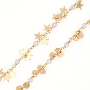 Pode incluir: Um colar de corrente dourada com pequenas estrelas douradas e contas redondas douradas. A corrente é intercalada com pérolas brancas.