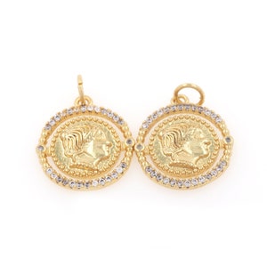 May include: Two gold-toned pendants with a raised profile of a woman's face on each. The pendants are surrounded by a circle of clear rhinestones.