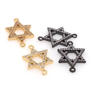 Op de afbeelding: Twee gouden en twee zwarte Davidster-charms met heldere kristallen accenten. De charms hebben aan elke kant een lus om aan sieraden te bevestigen.