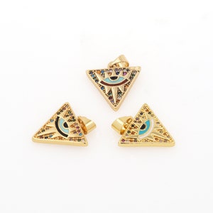 Puede incluir: Tres colgantes de triángulo dorado con un diseño de ojo malvado. Cada colgante está cubierto de piedras de cristal de colores y tiene un ojo azul con una pupila negra.