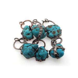 May include: A set of six turquoise stone charms with silver and copper accents. Each charm has a unique shape and is attached to a silver loop.