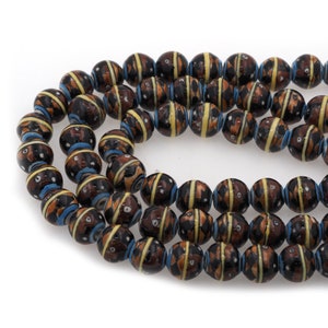 May include: A strand of brown, black, and yellow ceramic beads with a geometric pattern. The beads are round and have a glossy finish.