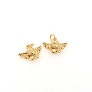 Op de afbeelding: Twee gouden engelbedels met vleugels en een slapend cherubijn gezicht. De bedels zijn perfect om een vleugje whimsy toe te voegen aan sieraden of knutselwerk.