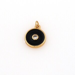 May include: Gold-toned pendant with a black enamel circle and a clear rhinestone in the center.