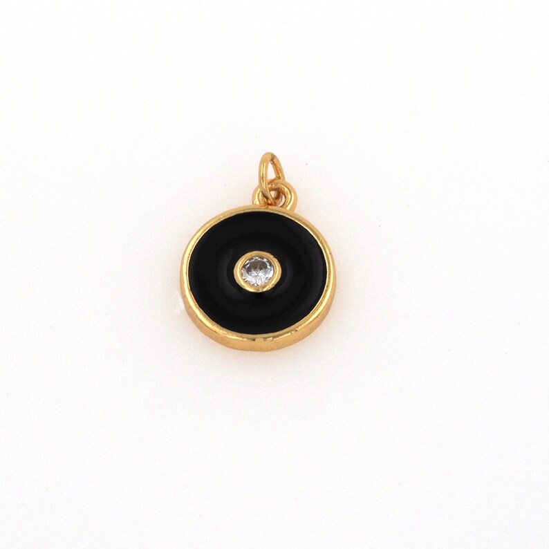 May include: Gold-toned pendant with a black enamel circle and a clear rhinestone in the center.