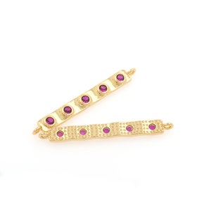 May include: Two gold-toned metal bar connectors with five purple gemstones each. The bars have a textured surface and are designed for jewelry making.