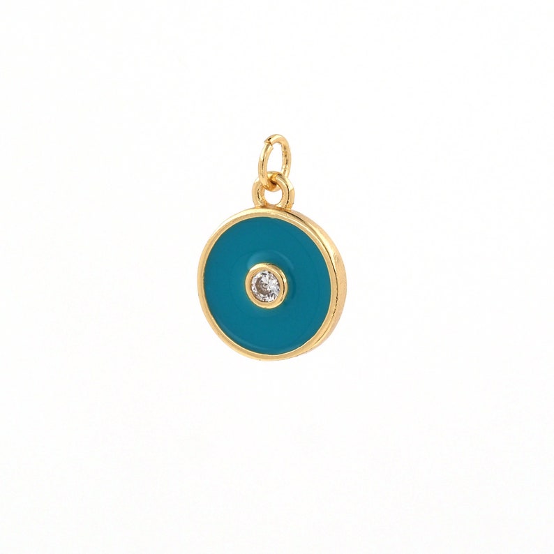 May include: Gold charm with a blue enamel circle and a small clear rhinestone in the center. The charm is designed to resemble a protective eye.