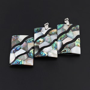May include: Three rectangular pendants made of abalone shell with a black and white geometric pattern. The pendants have a silver-toned metal bail.