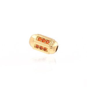 May include: Gold-toned bead with a rectangular design featuring a row of orange gemstones on each side.