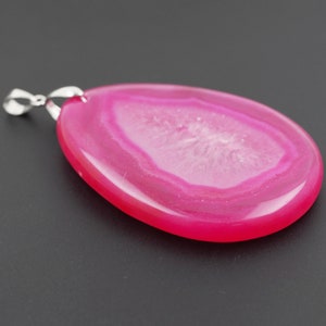 May include: A pink agate pendant with a silver bail. The agate has a white center with pink layers around it.