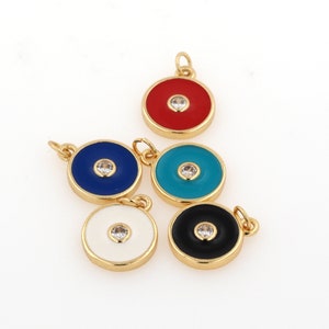 May include: Five gold-toned charms with a round, flat design. Each charm has a different colored enamel center with a clear rhinestone in the middle. The colors are red, blue, turquoise, white, and black.