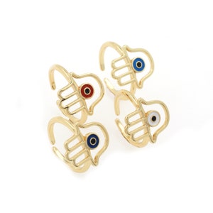 Pu&ograve; includere: Quattro anelli dorati con un design a mano di hamsa. Ogni anello ha un occhio blu con un centro di colore diverso: rosso, bianco, blu e nero.