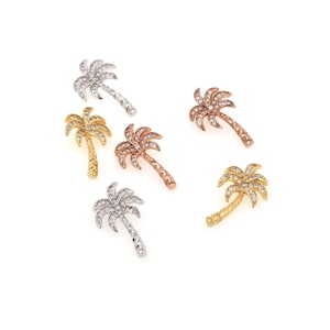 May include: Five palm tree charms with clear crystal accents. The charms are in silver, gold, and rose gold.