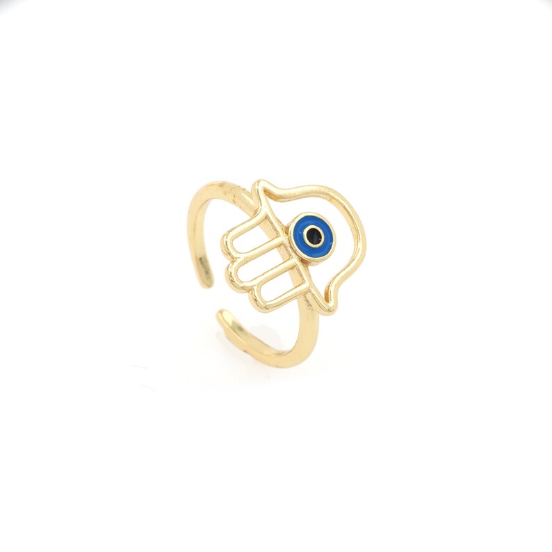 Pu&ograve; includere: Anello in oro con un design a mano di hamsa e un occhio turco blu al centro.