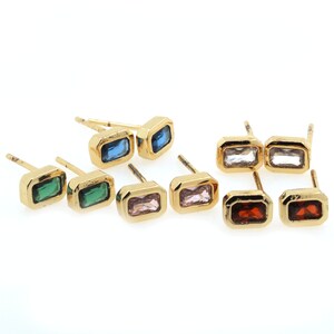 May include: A set of ten gold stud earrings with different colored rectangular gemstones. The earrings feature a variety of colors, including green, blue, pink, white, and red.