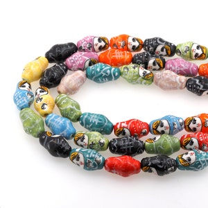 May include: A strand of colorful ceramic beads with painted faces. The beads are oval shaped and have a glossy finish.