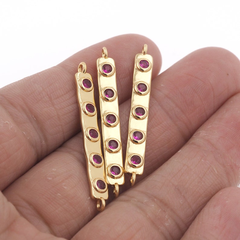 May include: Three gold-tone bar connectors with five pink rhinestones each. The connectors have a loop on each end for attaching to jewelry.