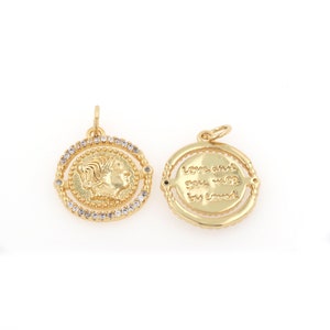 May include: Gold-tone pendant with a spinning design. One side features a profile of a woman's face, the other side reads "Love and you, always by heart".