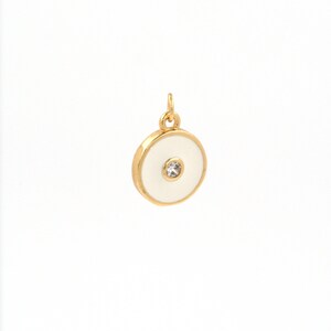 May include: A gold-toned pendant with a white enamel circle and a clear rhinestone in the center.