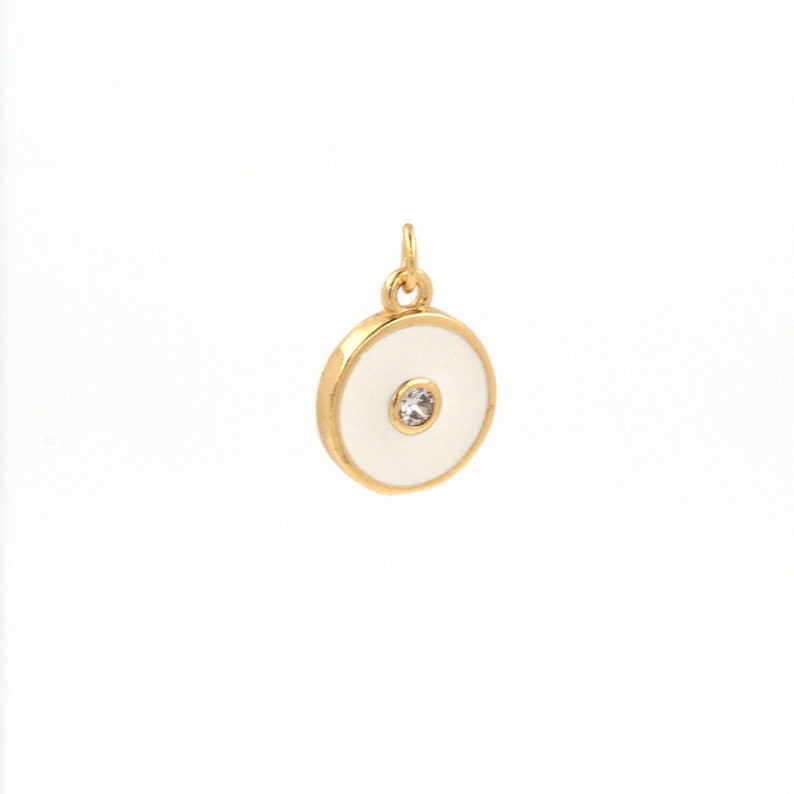 May include: A gold-toned pendant with a white enamel circle and a clear rhinestone in the center.
