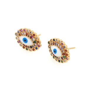Puede incluir: Un par de pendientes de tono dorado con un diseño de ojo turco blanco rodeado de piedras preciosas de colores.
