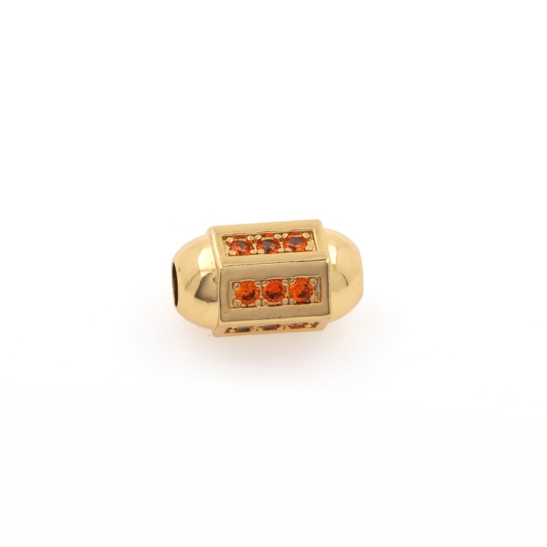 May include: A gold-toned bead with a rectangular design featuring orange gemstones. The bead is designed for use in jewelry making.