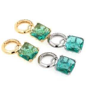 May include: A pair of dangle earrings with green square-shaped gemstones and gold and silver hoops.