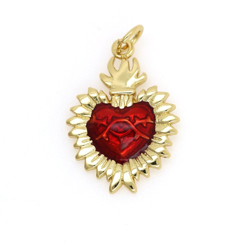 May include: Gold-tone pendant featuring a red enamel heart with a stylized eye and thorns, surrounded by a gold-tone flame design.
