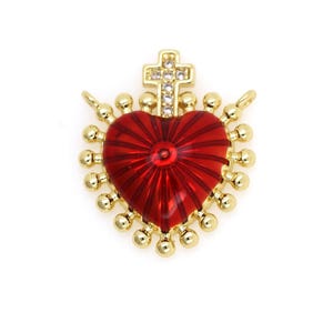 May include: Gold-tone charm featuring a red heart with a cross on top. The heart has a textured design and is surrounded by small gold beads.