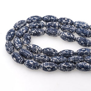 Peut inclure: Un collier de perles en céramique blanche avec des caractères chinois bleus et des motifs floraux. Les perles sont de forme ovale et ont une finition brillante.