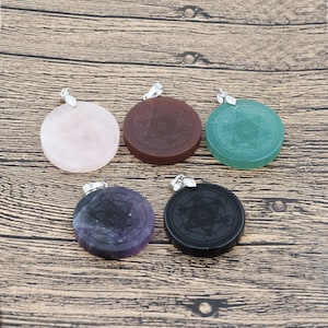 May include: Six round pendants with a silver bail, each featuring a different color and a geometric design. The colors are pink, brown, green, purple, and black.