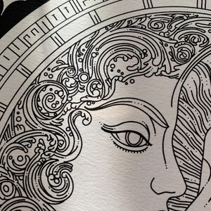 May include: A black and white line art illustration featuring a profile of a face with flowing, wave-like hair patterns. The design is enclosed within a circular frame decorated with a geometric Greek key border and set against a dark background.