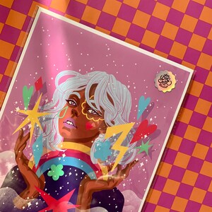 K&ouml;nnte beinhalten: Ein rechteckiger Kunstdruck in einer transparenten Schutzh&uuml;lle mit einer stilisierten Illustration einer Person mit hellblauem Haar, umgeben von farbenfrohen grafischen Elementen wie einem Regenbogen, einem gelben Blitz, Sternen und Herzen auf violettem Hintergrund.