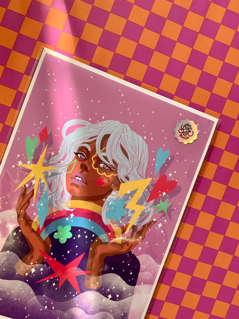 K&ouml;nnte beinhalten: Ein rechteckiger Kunstdruck in einer transparenten Schutzh&uuml;lle mit einer stilisierten Illustration einer Person mit hellblauem Haar, umgeben von farbenfrohen grafischen Elementen wie einem Regenbogen, einem gelben Blitz, Sternen und Herzen auf violettem Hintergrund.